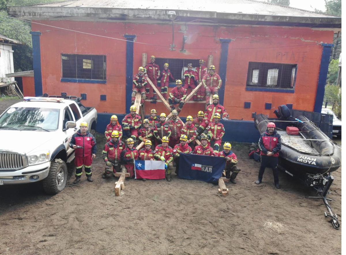 Equipo de ONG SAR Metropolitano en terreno junto a la bandera de Chile